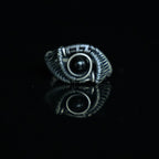 The Eclipse natural black obsidian ring with hand-shaped brass wirework, front view