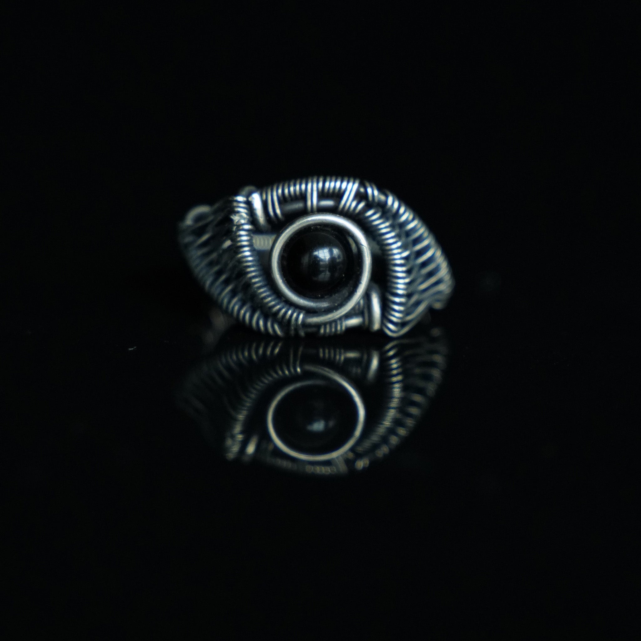 The Eclipse natural black obsidian ring with hand-shaped brass wirework, front view