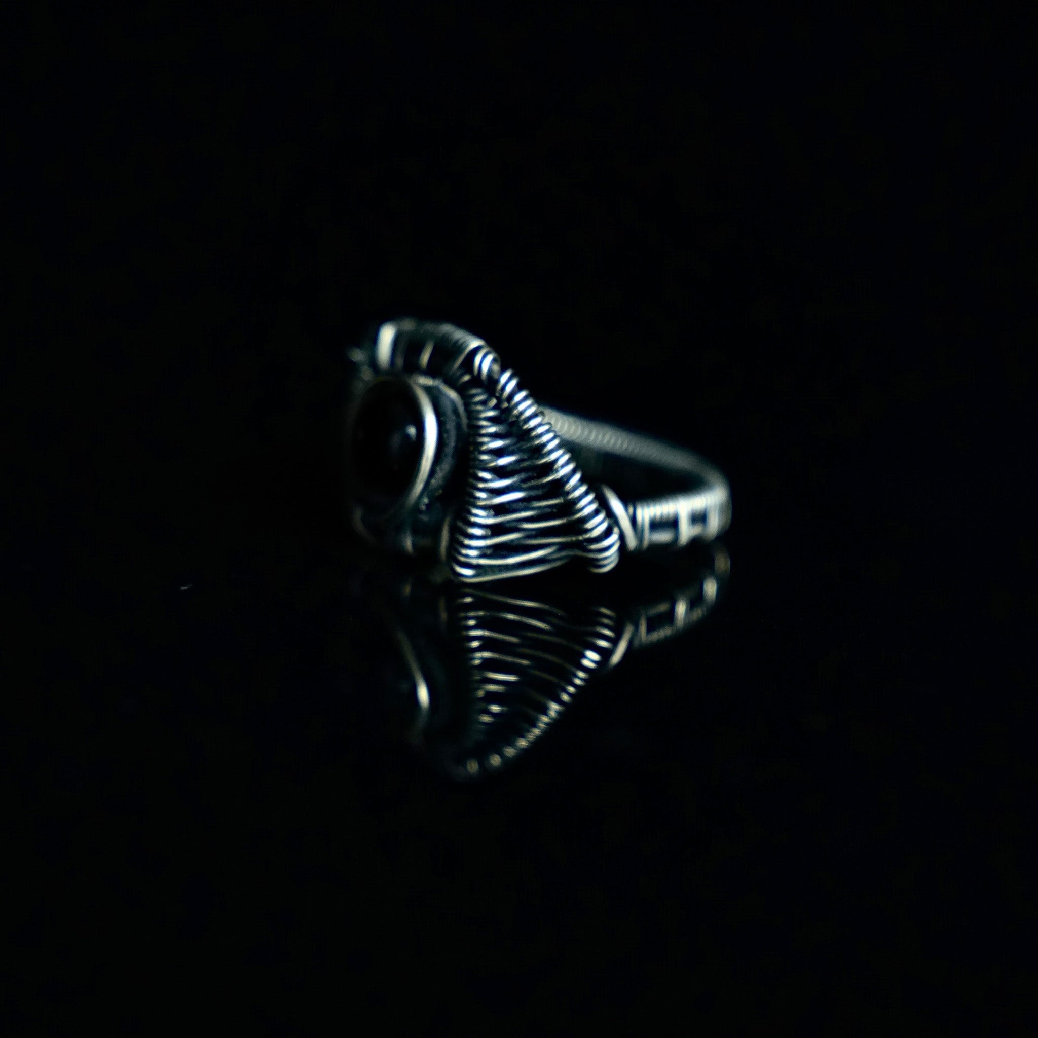 Side view of The Eclipse black obsidian ring showing its sculptural brass wirework and ringband