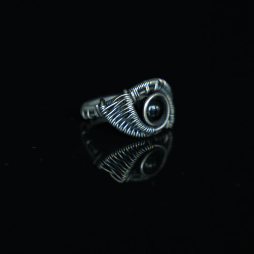 Three-quarter view of The Eclipse natural black obsidian ring showing its hand-shaped brass
wirework