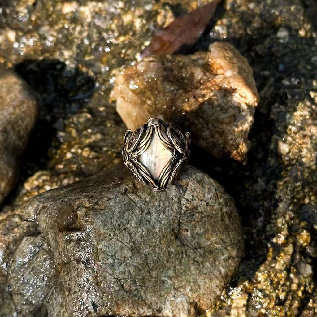 The Veil natural labradorite and brass wire-wrapped ring held for scale